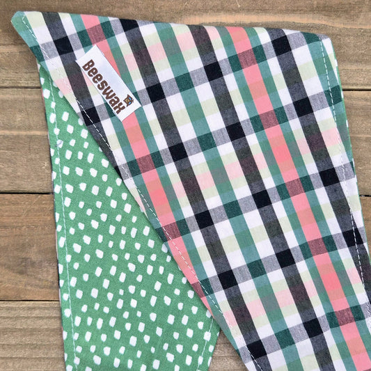 a colorful plaid bandana with a green polka dot pattern, placed on a wooden surface.
