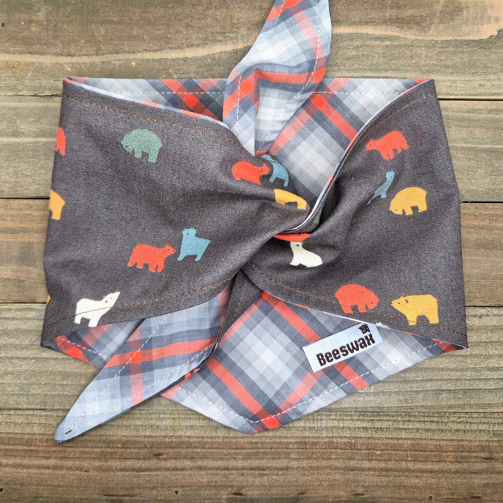 a plaid bandana with a pattern of colorful animal silhouettes, including bears, on a wooden surface.