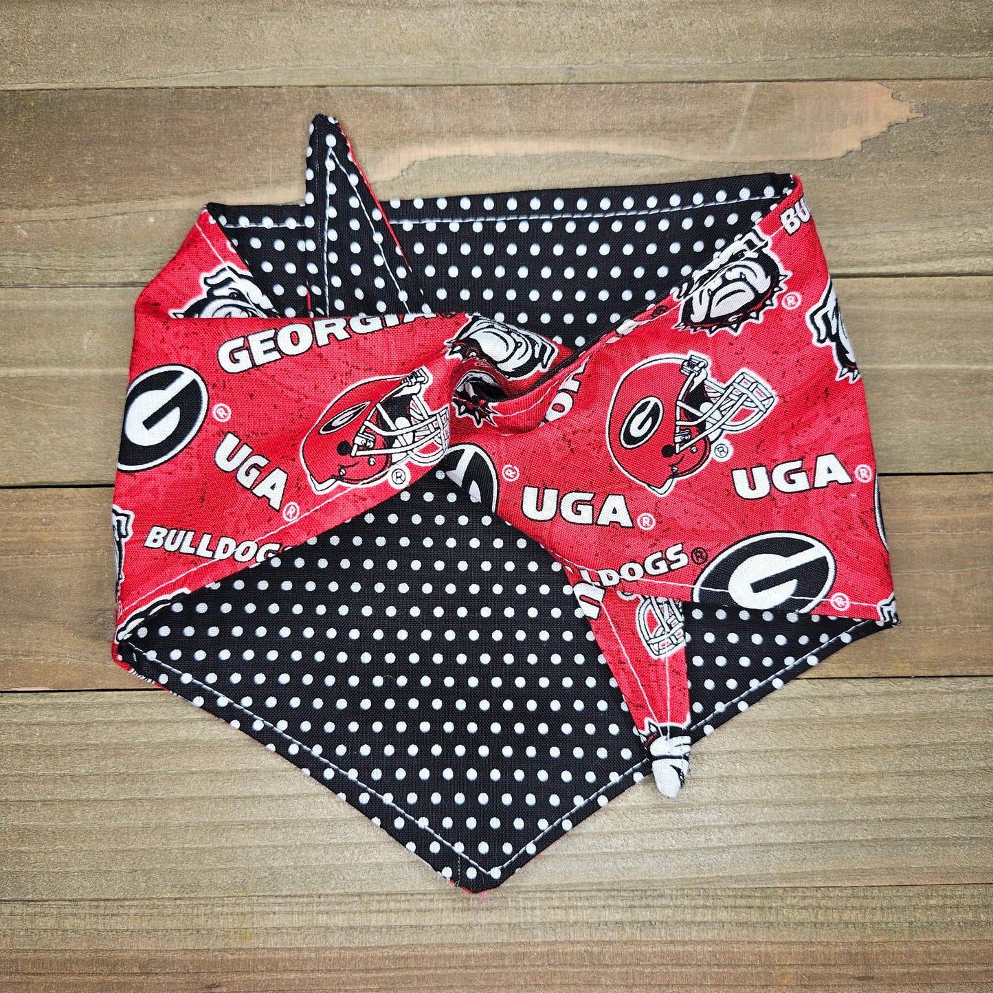 A red and black bandana with the Georgia Bulldogs football team logo printed on it, placed on a wooden surface.