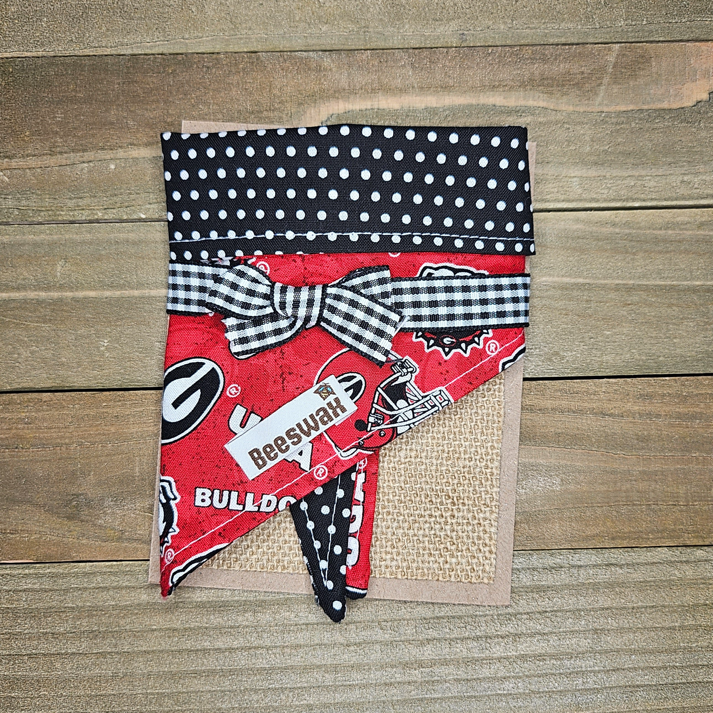 A red and black polka dot bandana with the word "BULLO" printed on it, tied with a black and white checkered bow.