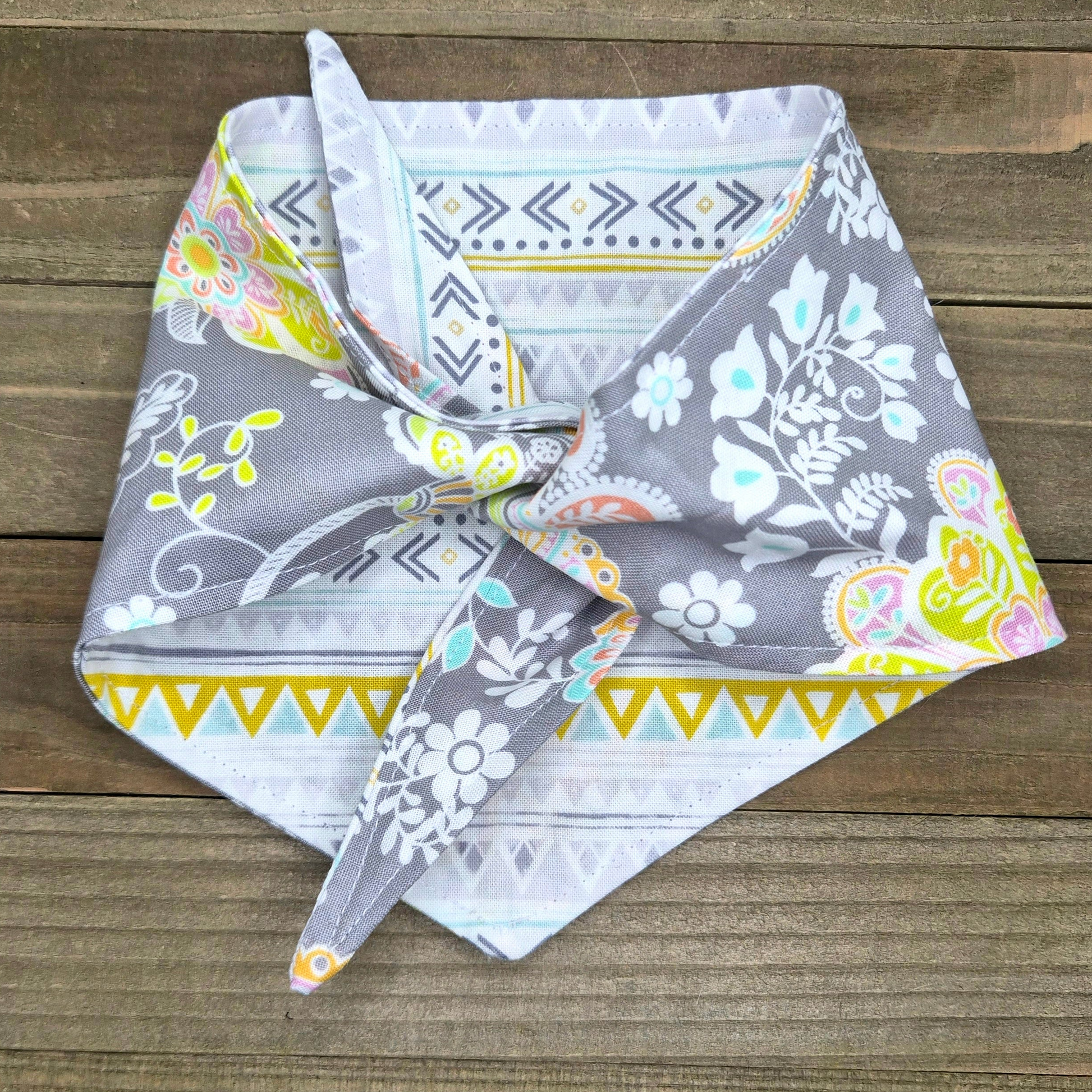 a gray and white patterned bandana tied in a knot, resting on a wooden surface.