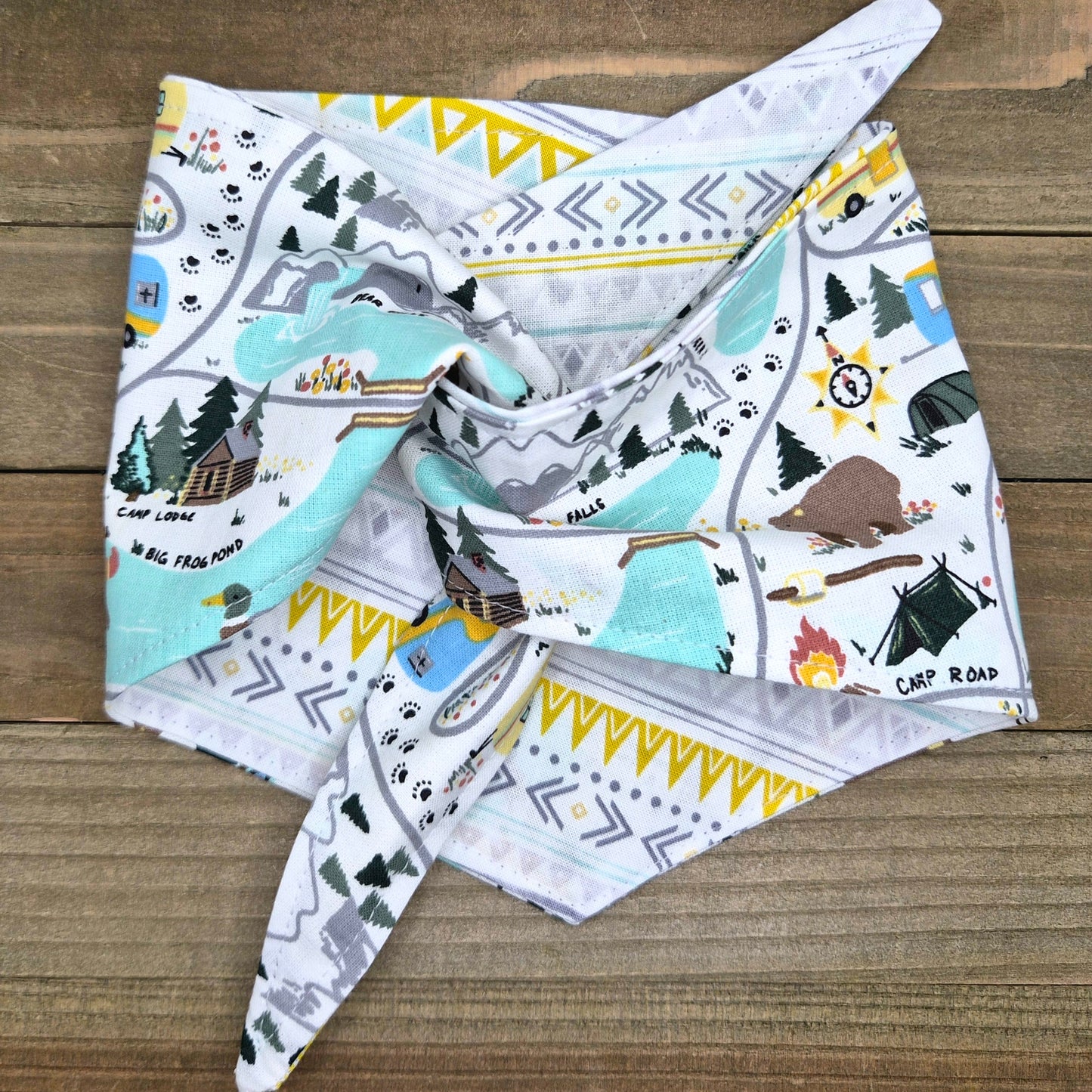 A colorful bandana with a pattern of camping and outdoor scenes, including tents, campfires, and mountains.
