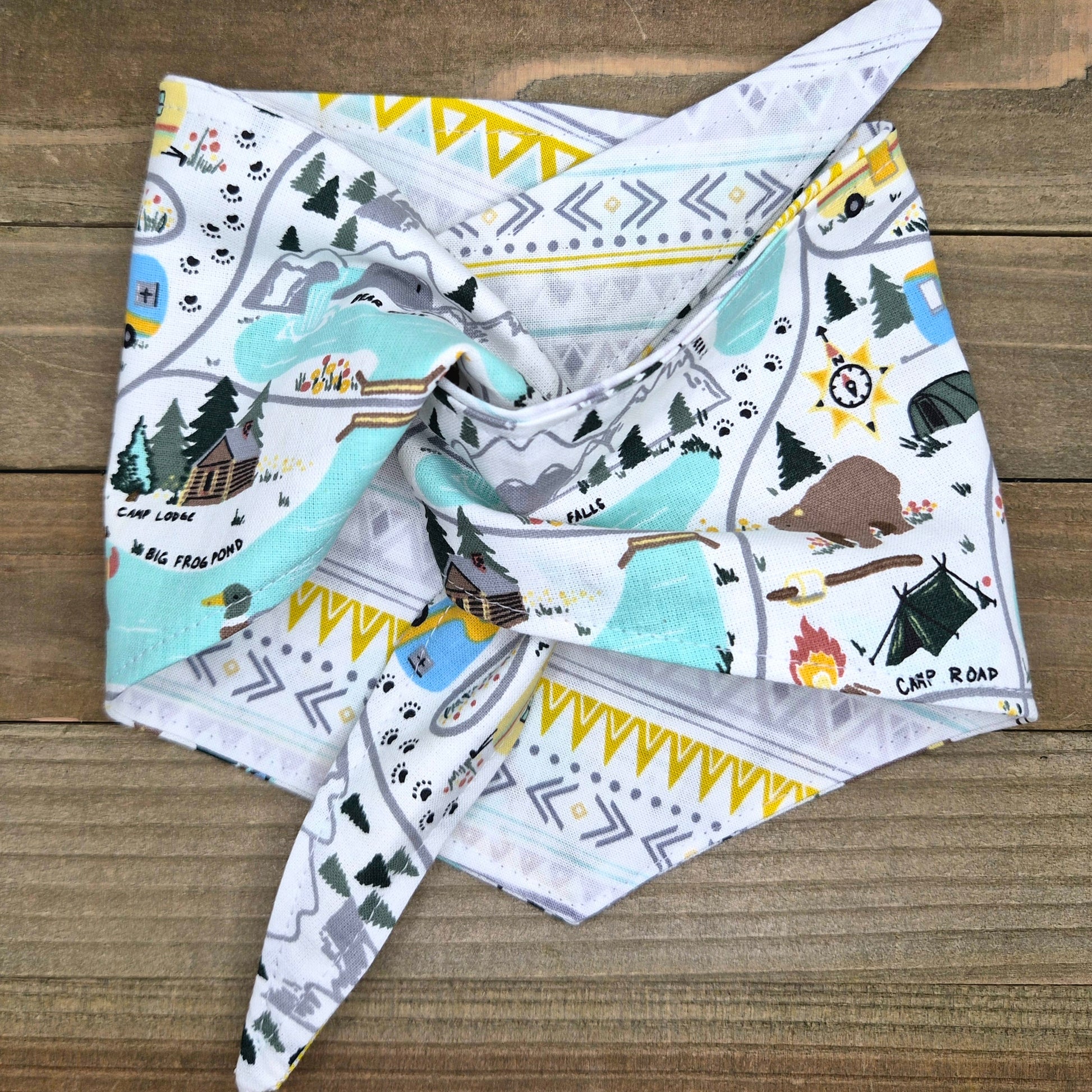 A colorful bandana with a pattern of camping and outdoor scenes, including tents, campfires, and mountains.