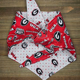 a red and white bandana with the Georgia Bulldogs logo printed on it, placed on a wooden surface.