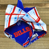 A blue and red plaid bandana with the word "BILLS" printed on it, folded in half and placed on a wooden surface.
