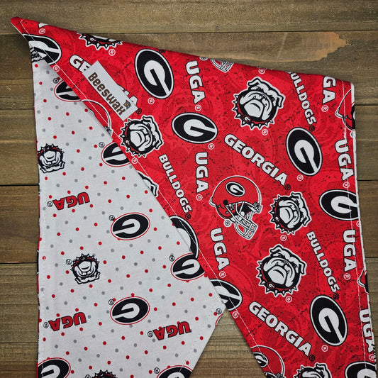 a red and white patterned fabric with the logos of the University of Georgia (UGA) and the University of Georgia (UGA).