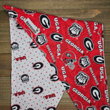 a red and white patterned fabric with the logos of the University of Georgia (UGA) and the University of Georgia (UGA).