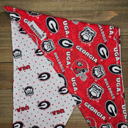 a red and white patterned fabric with the logos of the University of Georgia (UGA) and the University of Georgia (UGA).