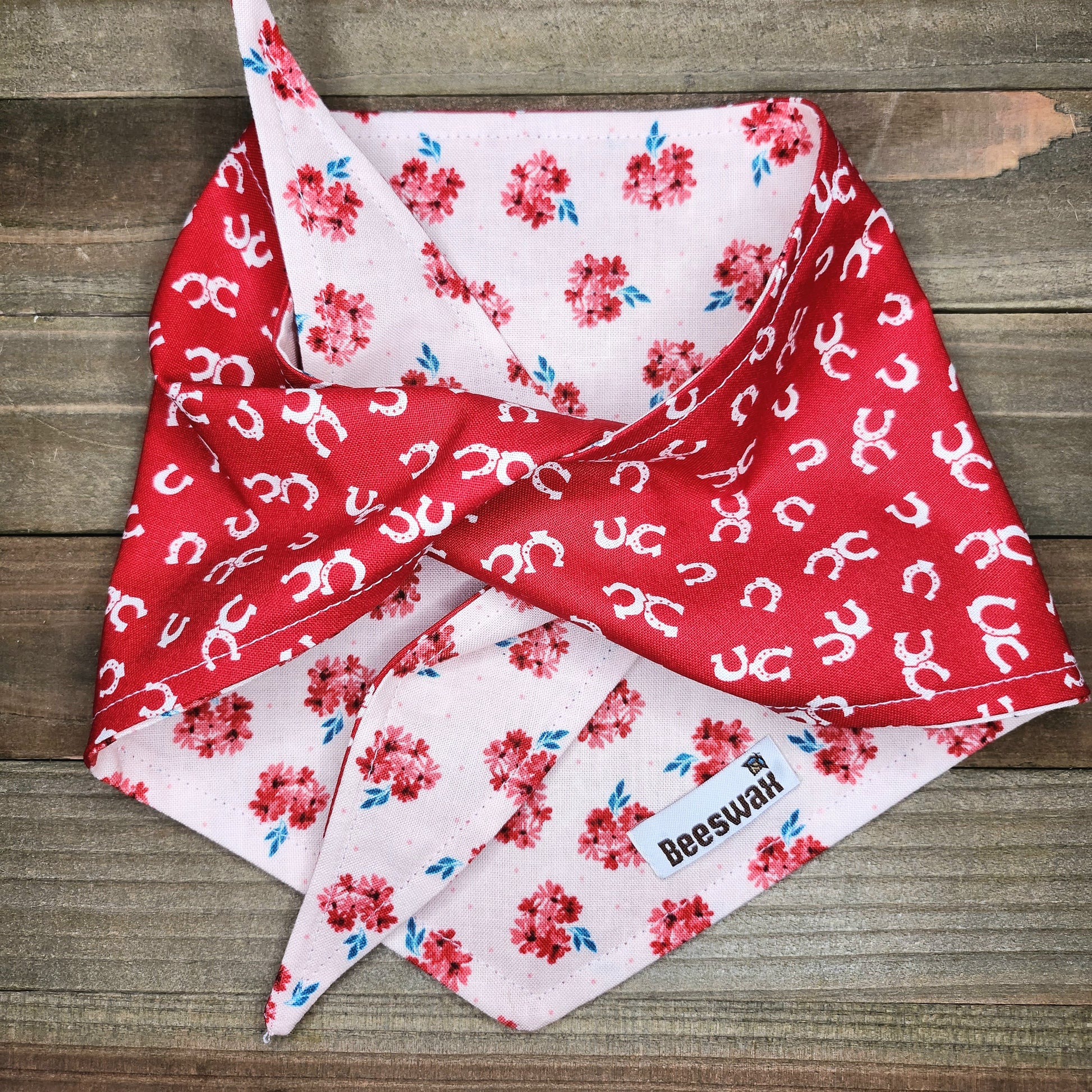 A red and white floral bandana is folded and placed on a wooden surface.