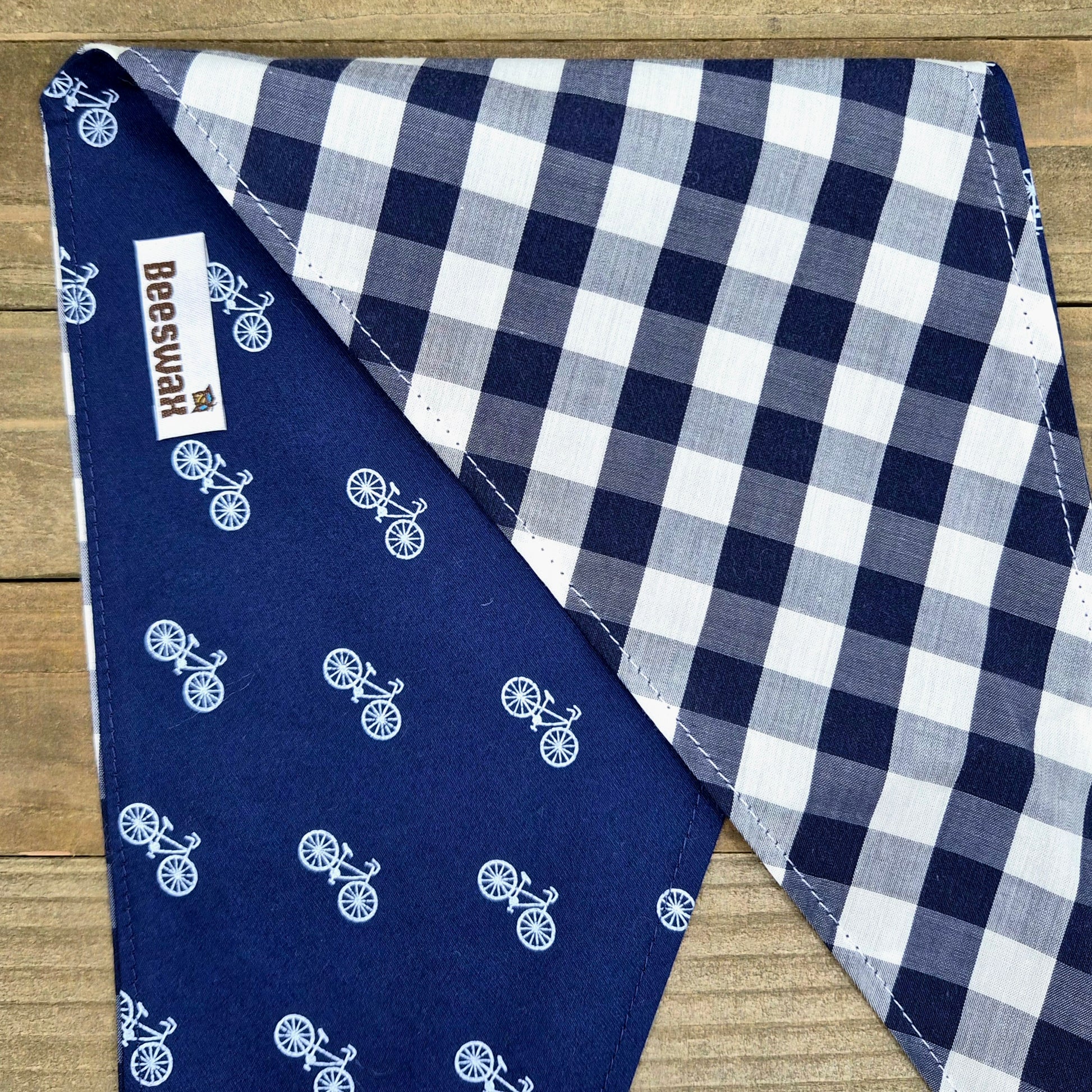 a blue and white checkered fabric with a bicycle pattern on it, placed on a wooden surface.