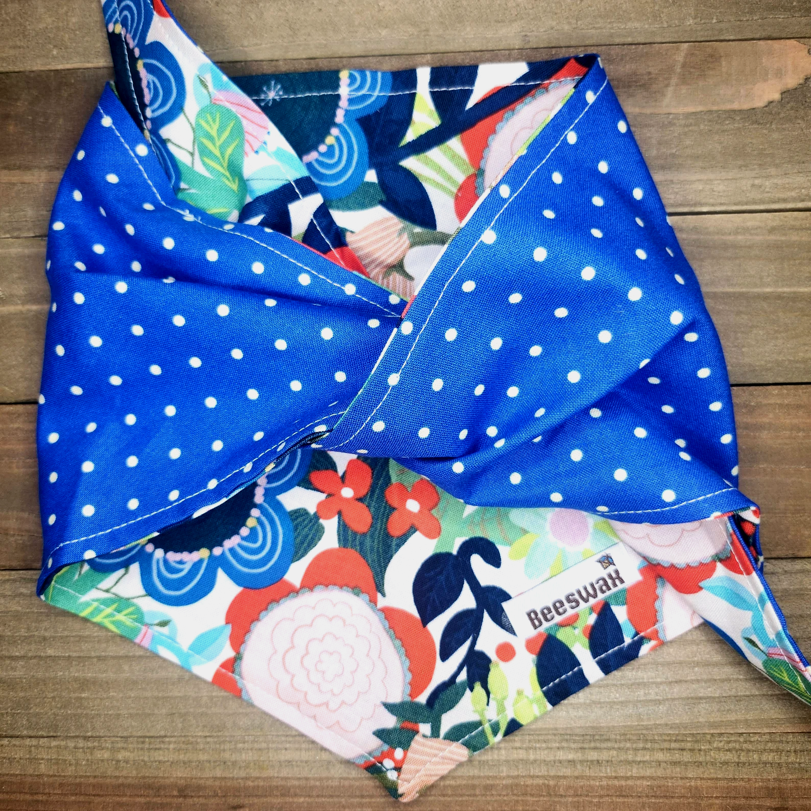 a colorful floral pattern with blue polka dots, including flowers, leaves, and other decorative elements, laid out on a wooden surface.