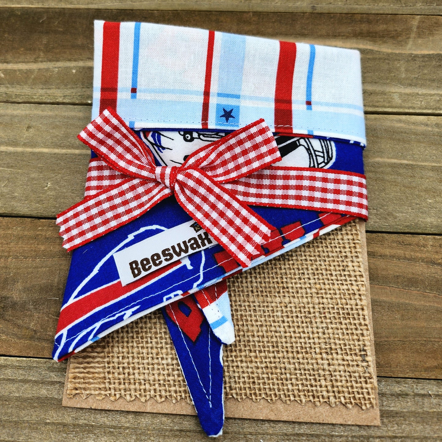 A red and white checkered bandana with a bow tied around it, placed on a burlap surface.