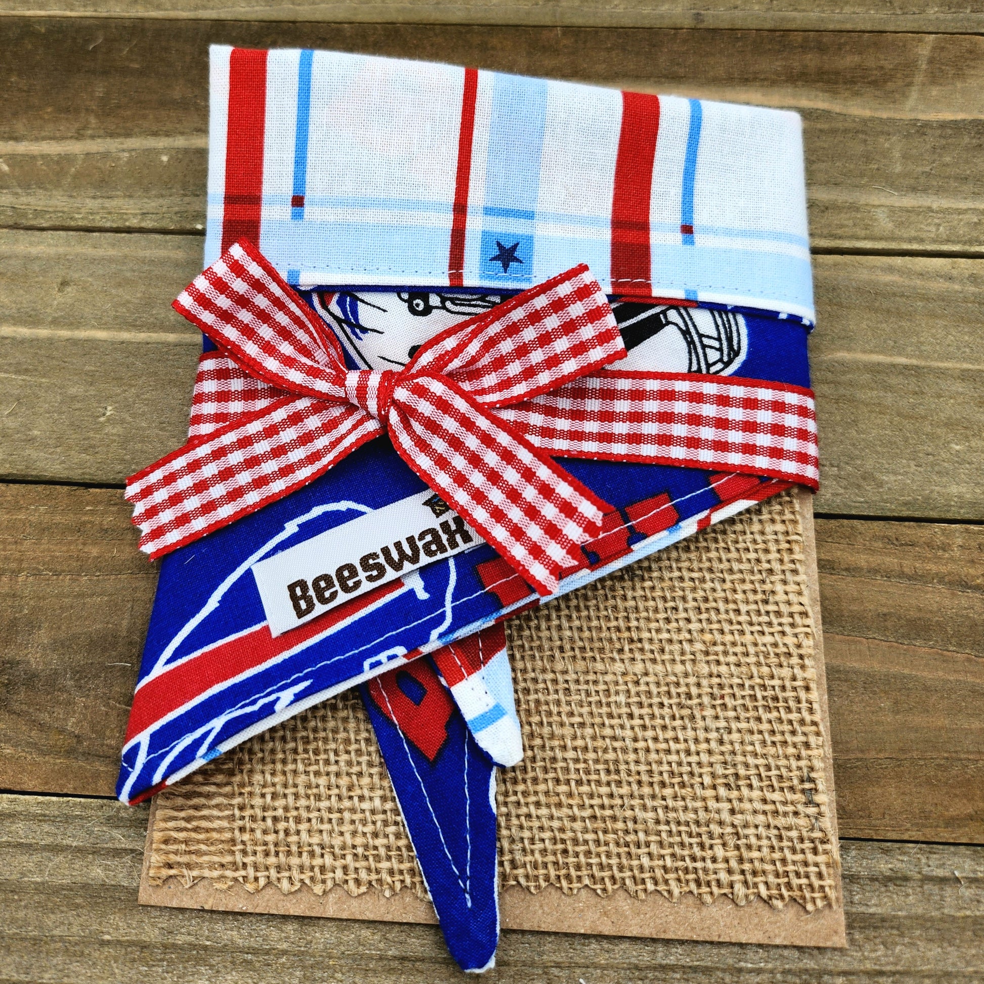 A red and white checkered bandana with a bow tied around it, placed on a burlap surface.