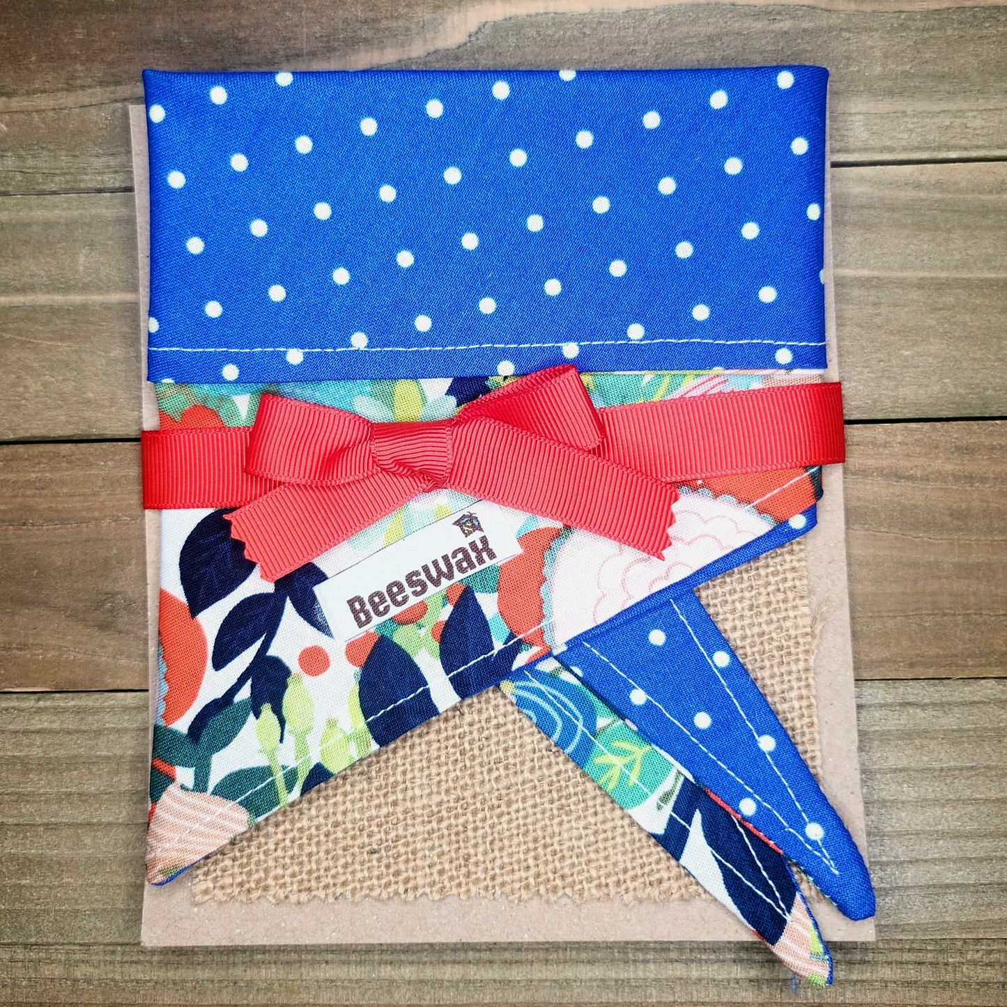 A blue fabric with white polka dots, tied with a red ribbon, and a small floral pattern. The fabric appears to be a part of a larger fabric or material, possibly a quilt or a decorative piece.