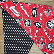 a red and black dog bandana with the Georgia Bulldogs football team logo printed on it, placed on a wooden surface.
