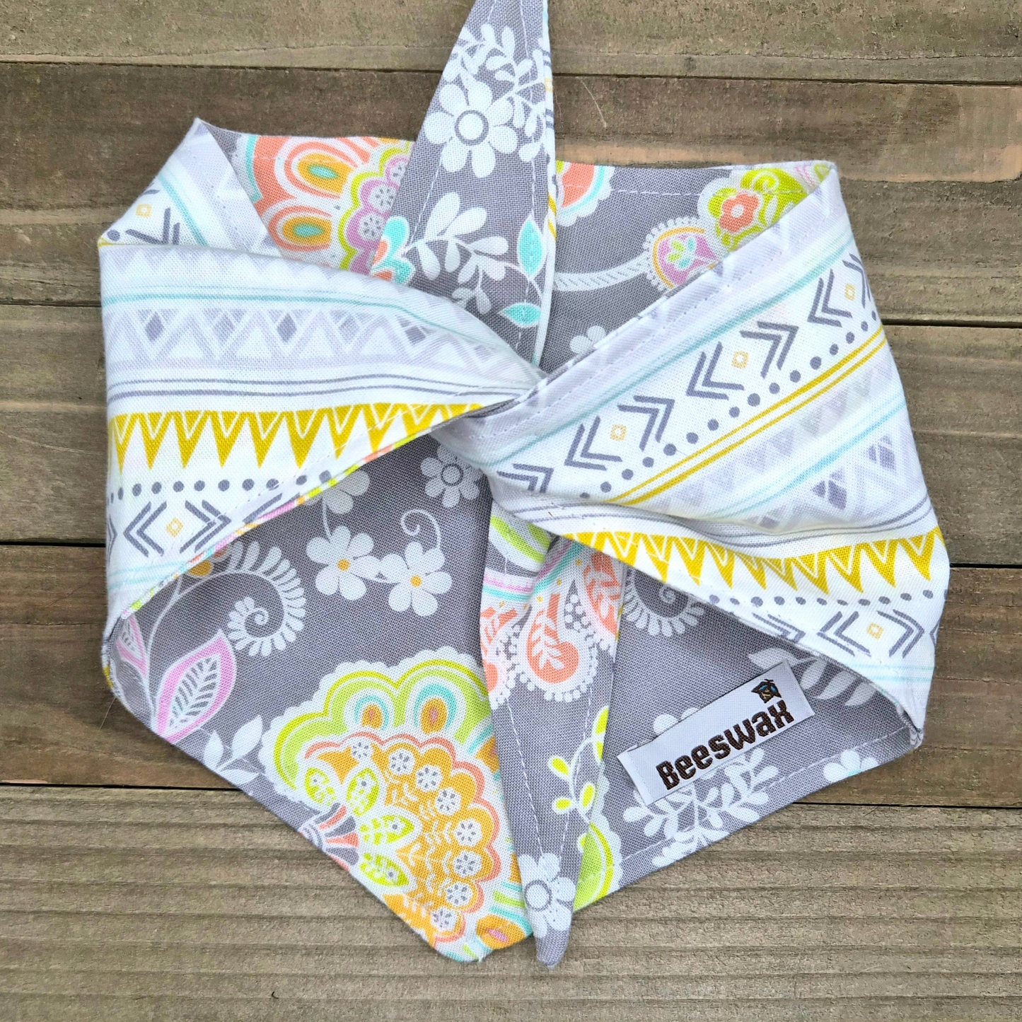 A colorful patterned bandana is folded and placed on a wooden surface.