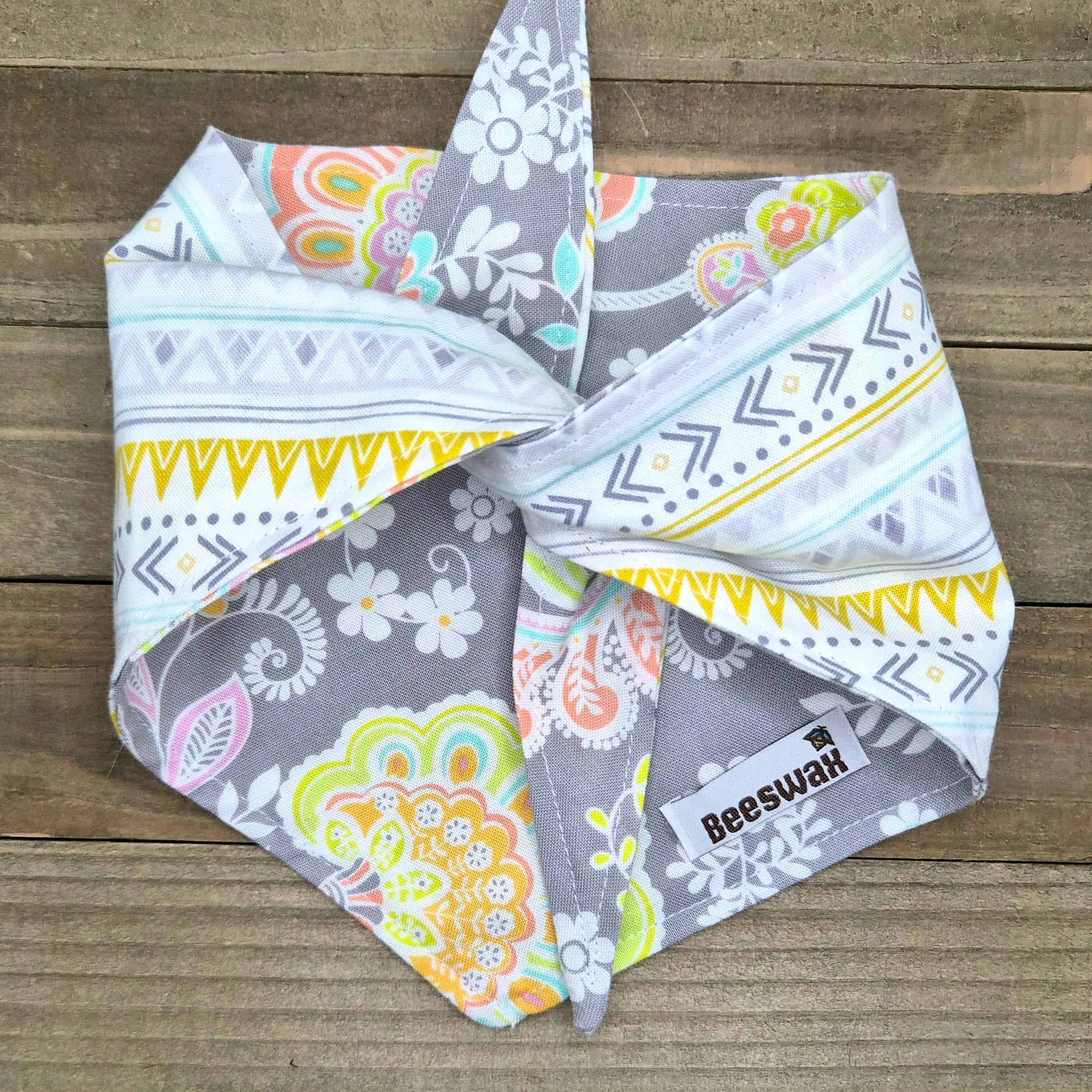 A colorful patterned bandana is folded and placed on a wooden surface.