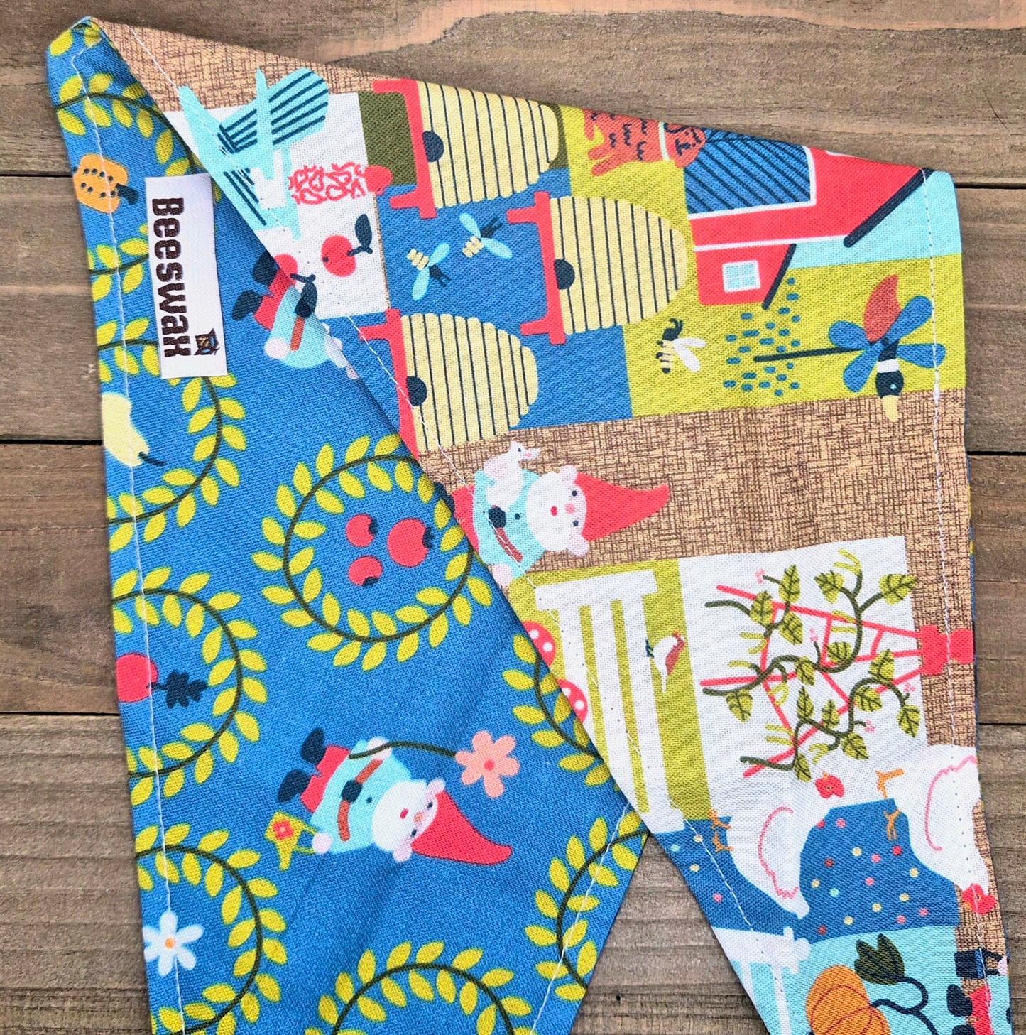 a colorful fabric with various patterns and designs, including gnomes, flowers, and other whimsical elements.