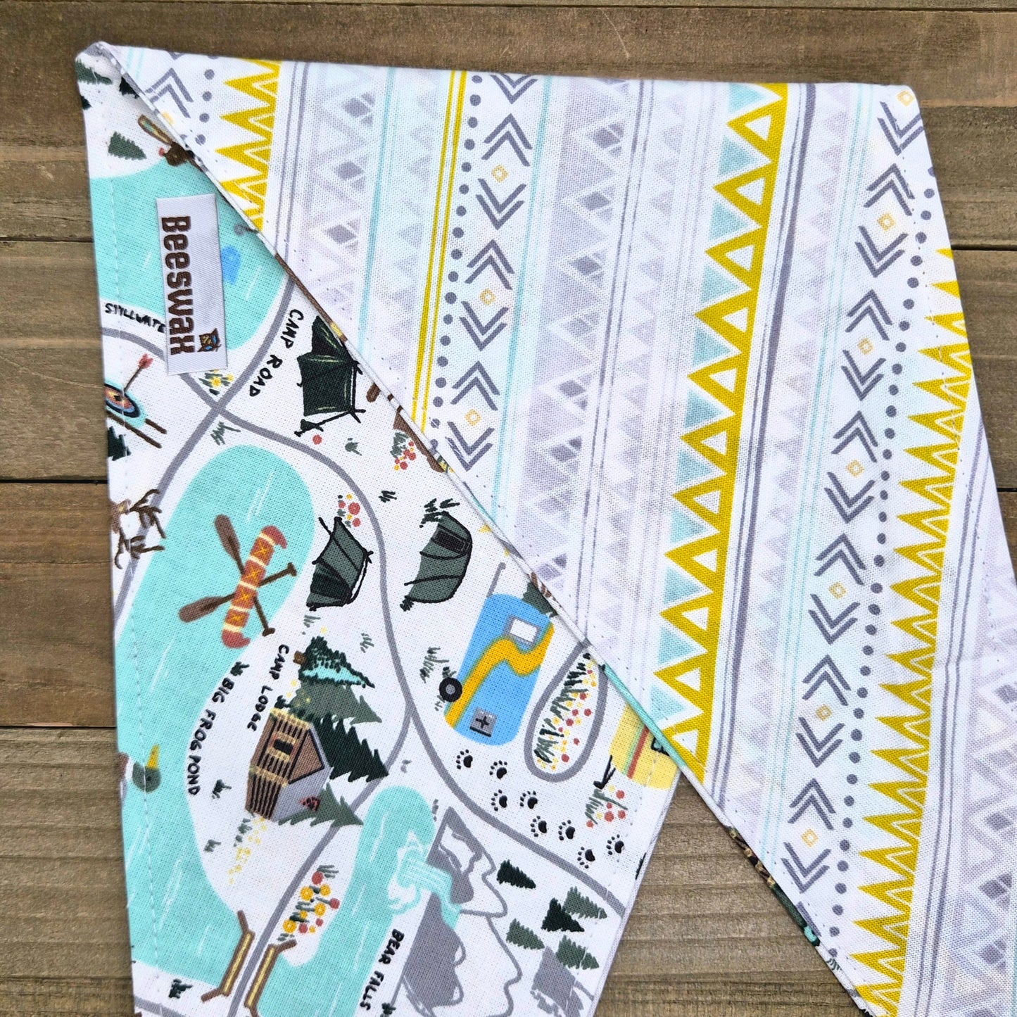 a colorful patterned fabric with various illustrations and designs, including a map, a boat, and other outdoor elements.