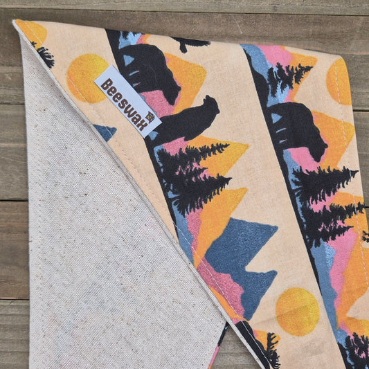 a colorful fabric with a pattern of mountains, trees, and a bear.