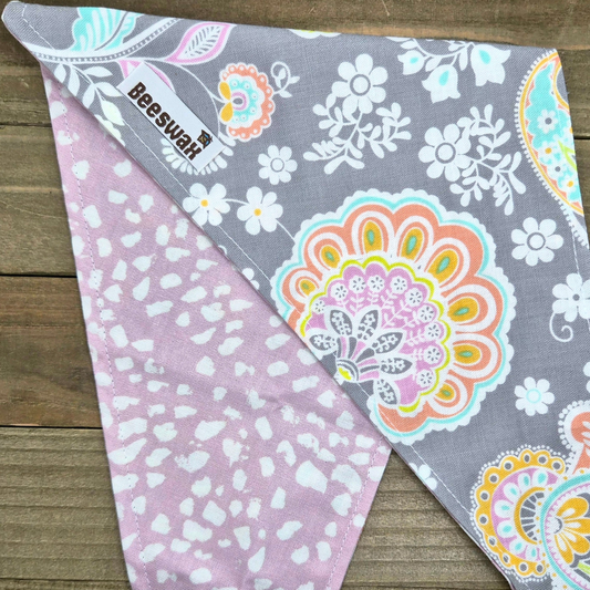 a gray and pink patterned bandana with a floral design, placed on a wooden surface.