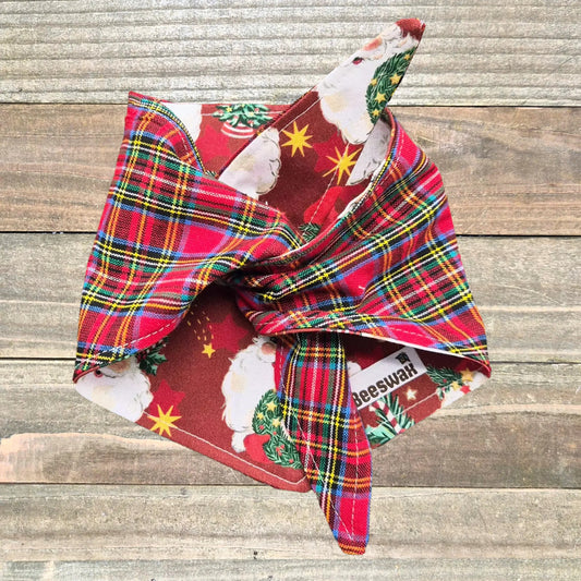 A colorful plaid bandana with a Christmas tree pattern is displayed on a wooden surface.