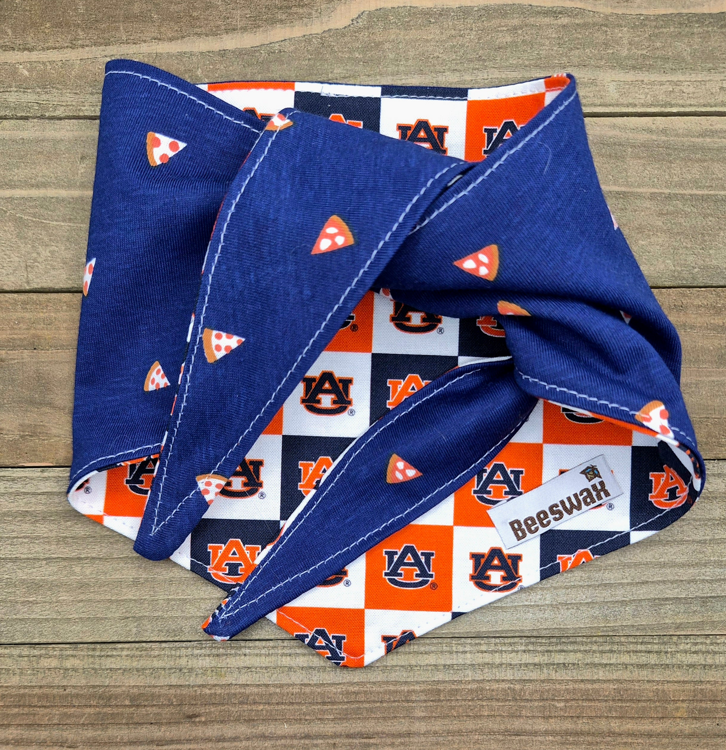 a blue bandana with a pattern of orange and white checkerboard squares, along with the text "Beeswax" printed on it.